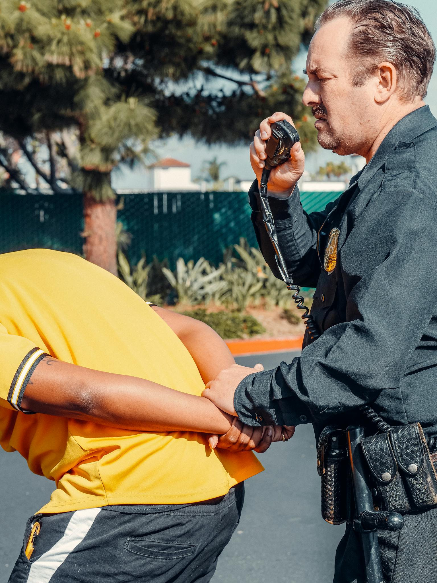 Law enforcement officer detains a suspect in daylight.